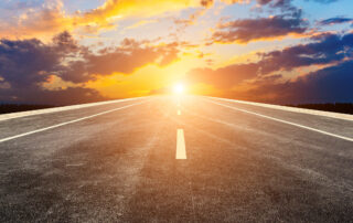 An empty highway straight ahead in the setting sun