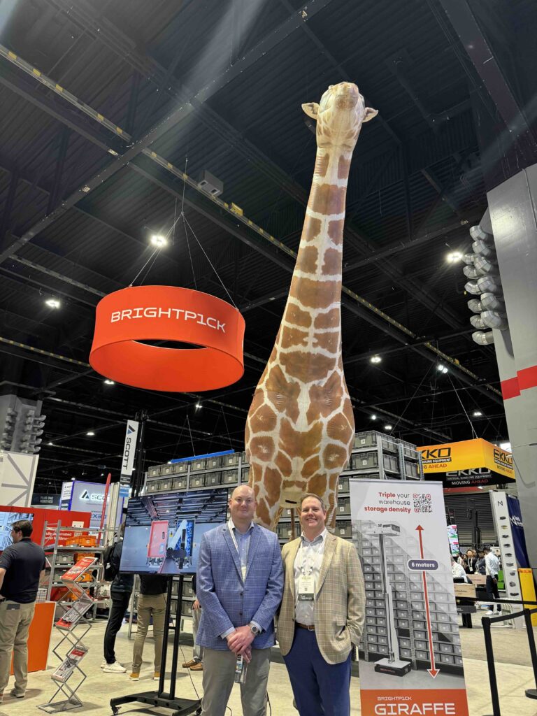 team members pose in front of giraffe at tradeshow